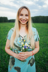 Naklejka na ściany i meble A woman in a light blue dress. A woman with a bouquet of wild flowers. A woman in nature.Natural beauty.unity with nature.Video portrait of a beautiful girl.