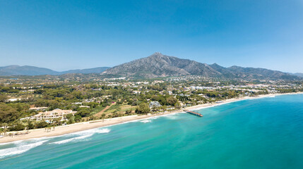 Unique aerial view of luxury and exclusive area in Marbella, golden mile beach, view of Puente Romano Bridge and in background famous La Concha mountain. Emerald water colour 