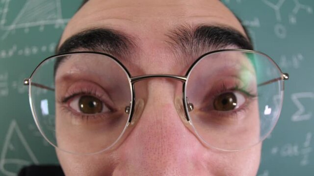 funny video of a school geek nerd putting his eyeglasses on his face and staring at the camera.