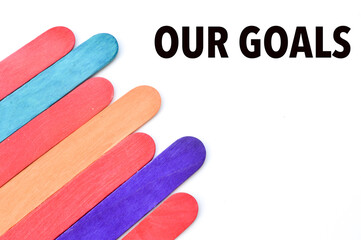 Selective focus of colorful ice cream sticks over white background written with text OUR GOALS. Business and education concept.