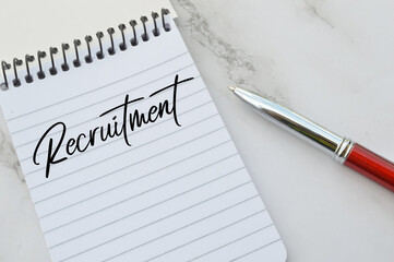 Top view of pen and notebook written with text RECRUITMENT. Business concept.