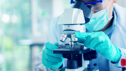 Scientist or doctor use microscope to test for the coronavirus (COVID 19). Or a new flu virus to save people life In the lab Or hospital. Success in research the treatment of patient
