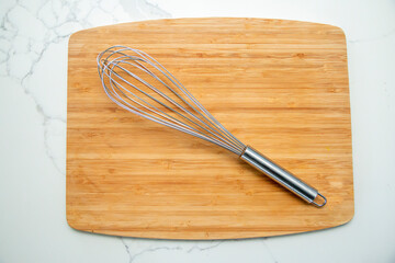 Metal whisk on a wooden cutting board