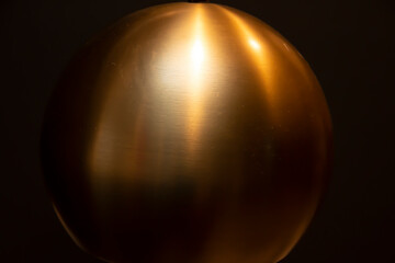 Shiny reflective bronze sphere at night