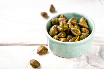 Marinated capers in a ceramic bowl. Edible flower buds of Capparis spinosa, caper bush or Flinders rose on a light background