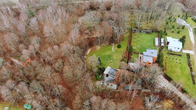 Small rural village from drone point of view with leafless trees and bendy river