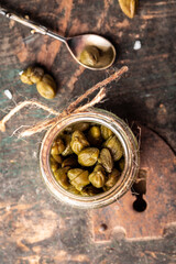 Pickled caper berries in jar. Delicious ingredients for cooking Mediterranean, Italian, Spanish, French cuisine. top view. vertical image, place for text