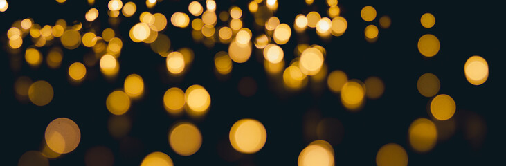 Golden bokeh lights banner background, abstract illumination texture in the dark