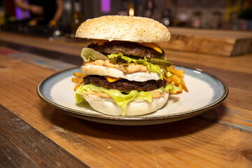 A classic home made burger and chips on a wooden table