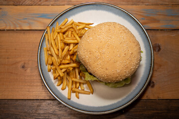 A classic home made burger and chips on a wooden table