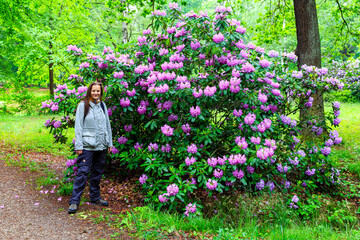 woman in front of Pacific rhododendron, blooming time at the rhododendron park Kromlau, saxony, Germany