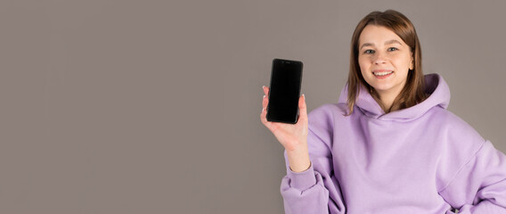 Naklejka premium Portrait of a confident attractive girl showing blank screen mobile phone isolated over gray background