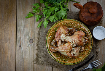 Hearty lunch: Chicken legs baked in milk on a plate on a wooden table