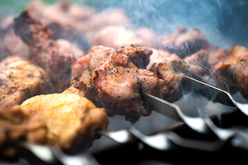 Shashlik or shish kebab preparing on barbecue grill over hot charcoal. Grilled pieces of pork meat on metal skewers.