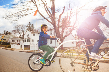 Portrait of a little boy ride on a tow tandem bike attached to father on urban street view from side