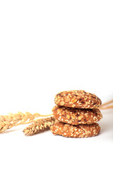 a pile of whole grain cookies and ears of wheat isolated on white background