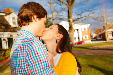Obraz premium Young happy couple kiss close portrait stand in public park profile view
