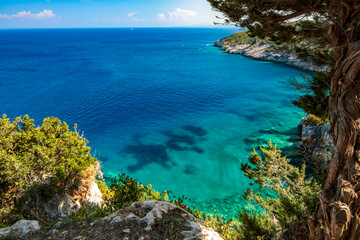 view of the coast on the Greek island of Zakynthos. The sea is clear blue and the sky blue with white clouds. © Tereza