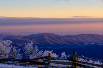 Devil's Knob Overlook – Purple and pink sky over Blue Ridge Mountains with ice covered trees and split rail fence in foreground