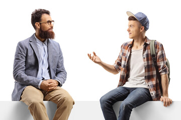 Man and a teenage male student sitting on a panel and talking