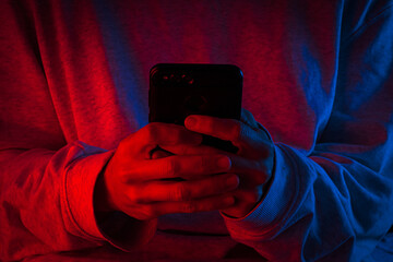 Manos sujetando un smartphone, iluminado con luces rojas y azules