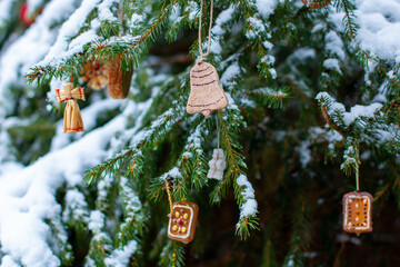 Wooden and handmade ornaments on Christmas tree in the snow