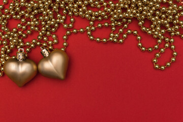 Red glossy hearts with golden pearls on a red background