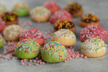 Fototapeta na wymiar Colorful sweet small doughnuts with sprinkles and a cup of tea