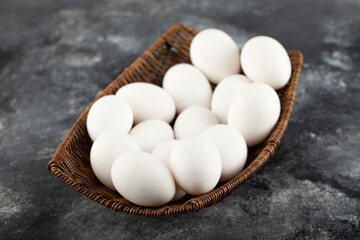 A wooden wicker full of white raw chicken eggs