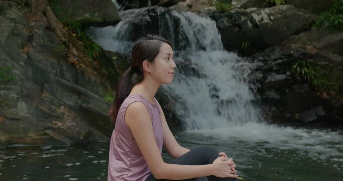 Sport woman sit beside waterfall