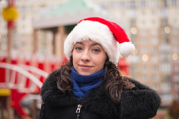 Portrait of a beautiful girl in a santa claus hat on a city