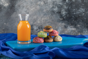 A glass bottle of juice with colorful doughnuts