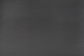 Black cardboard background with closeup on a piece of black colored paper.