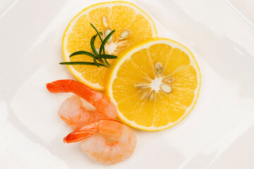 Two lemon wedges and two shrimps on white plate.