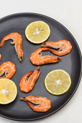 Shrimp and lemon wedges on black plate.