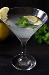close-up margarita cocktail in the bar. martini glass of cocktail with olives and lemon with green mint on wooden background. Glasses for martini on the black table. copy space.alcohol drinks.vertical