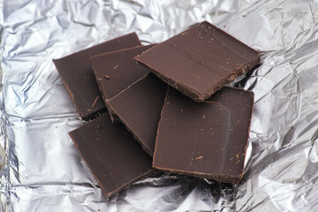 Pieces of dark broken chocolate on wrapping foil