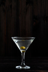 margarita cocktail in the bar. martini glass of cocktail with olives on wooden background. Glasses for martini on the black table. copy space. alcohol drinks. vertical