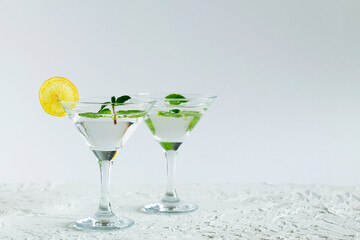 cocktail in the bar. two martini glasses of cocktail with green mint and lime on white background. alcohol drinks. Glasses for cocktail with lemon on the table. copy space