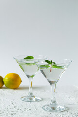 margarita cocktail in the bar. two martini glasses of cocktail with green mint and lime on white background. alcohol drinks. Glasses for cocktail with lemon on the table. copy space. vertical