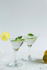 margarita cocktail in the bar. two martini glasses of cocktail with green mint and lime on white background. alcohol drinks. Glasses for cocktail with lemon on the table. copy space. vertical