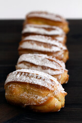 French eclairs on table. vanilla eclairs or profiteroles on a wooden table. Traditional french tasty dessert on dark background. copy space. vertical
