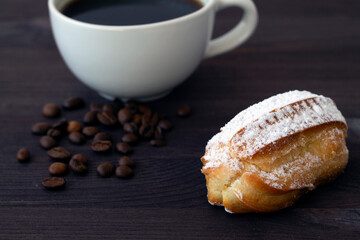 close-up Traditional french tasty dessert on dark background. homemade vanilla eclairs or profiteroles on a wooden table. copy space. cup of black coffee with beans.