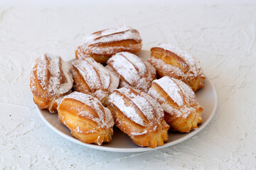 homemade vanilla eclairs on a plate on a white table. copy space. Traditional french tasty dessert on a background.