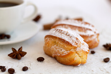 Close-up vanilla eclair on a plate on white background. Coffee cup with coffee beans and anise star, cinnamon sticks on white background. copy space. Traditional french tasty dessert.