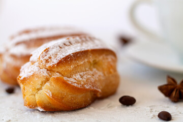 Close-up vanilla eclair on a plate on white background. Coffee cup with coffee beans and anise star, cinnamon sticks on white background. copy space. Traditional french tasty dessert.