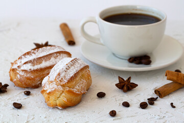 Traditional french tasty dessert. vanilla eclair on a plate on white background. Coffee cup with coffee beans and anise star, cinnamon sticks on white background. copy space