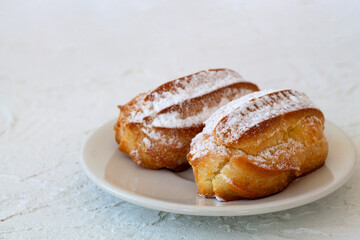 vanilla eclair on a plate on white background. Traditional french tasty dessert. copy space