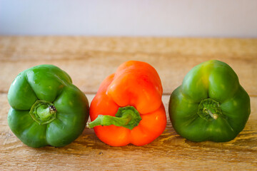 Red and green bell peppers on a wooden board
