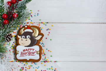 Obraz na płótnie Canvas Gingerbread in the form of a bull, a Christmas tree with a pine cone and berries on a white wooden background. Happy new year 2021! Copy space for text